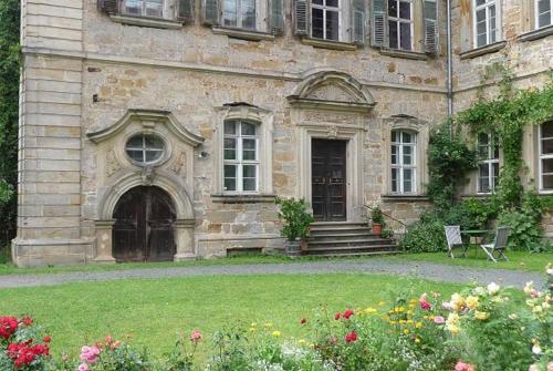an old stone building with a door and some flowers at Ferienzimmer im Schloss Burgpreppach in Burgpreppach