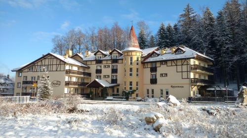 a large building in the snow with trees at Nowa - Ski SPA Hotel in Karpacz