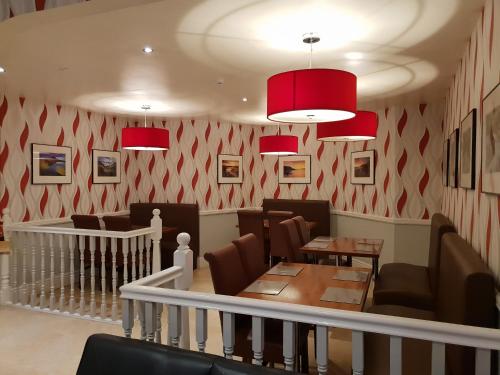 a restaurant with chairs and tables and red walls at Ascot Hotel in Douglas