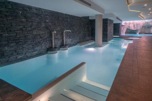 a swimming pool with blue lighting and a brick wall at Le Kaïla in Méribel