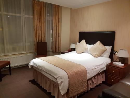 Habitación de hotel con cama grande con sábanas y almohadas blancas. en Ascot Hotel, en Douglas