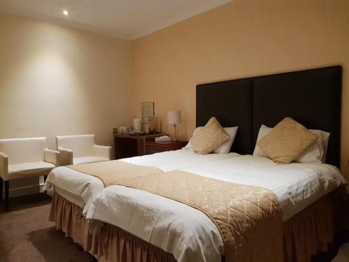 a hotel room with a large bed and a chair at Ascot Hotel in Douglas