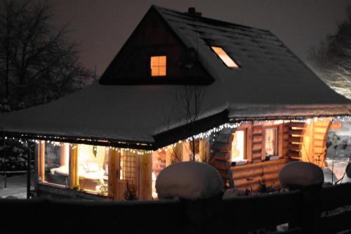 a house covered in snow with lights on it at CHATA PACHNĄCA LASEM in Andrychów