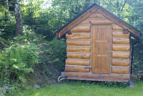 a wooden out house with a door in the grass at CHATA PACHNĄCA LASEM in Andrychów