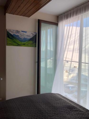 ein Schlafzimmer mit einem Bett und einem großen Fenster in der Unterkunft Ski Heaven in Gudauri