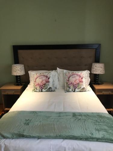 a bed with pillows and two lamps on two tables at TeBeacon Accommodation in East London