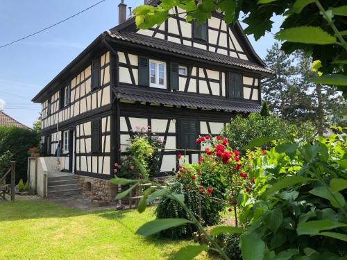 a black and white house with flowers in the yard at La Stube de Marinette 5 étoiles in Hipsheim