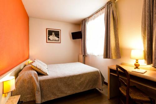 a bedroom with a bed and a desk and a window at Hotel Le Lumière in Lyon