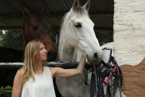 a woman standing next to a white horse at Hosteria Papagayo Cotopaxi in Machachi