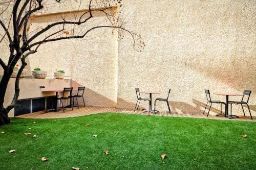 a patio with two tables and chairs and green grass at Hotel Le Lumière in Lyon