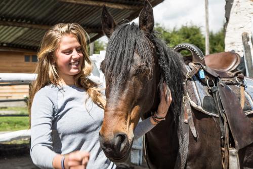 a woman standing next to a brown horse at Hosteria Papagayo Cotopaxi in Machachi