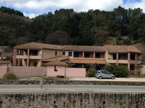 a building with a car parked in front of it at Résidence Le Grand Virage in Pont-de-Labeaume
