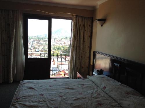 ウルアパン・デル・プログレソにあるHotel Real de Uruapanのベッドルーム1室(ベッド1台、大きな窓付)