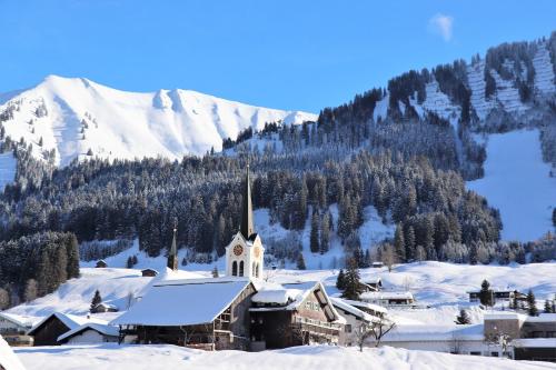a church covered in snow with a mountain in the background at Gatterhof in Riezlern