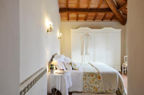 a bedroom with a white bed and a table at Agriturismo Il Rigo in San Quirico dʼOrcia