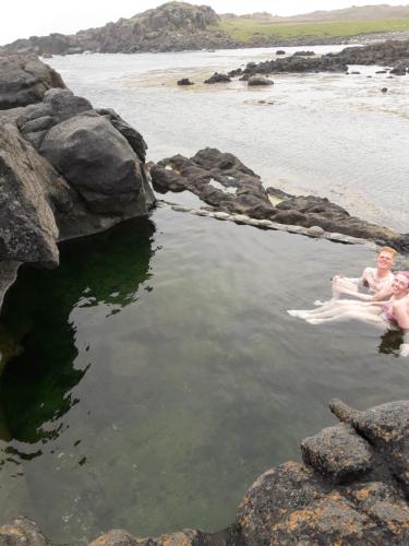 two people sitting in a body of water at Hvammur 2 Bjarg with private hot tub in Drangsnes