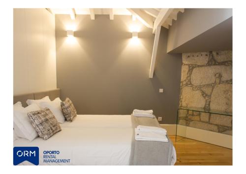 um quarto com uma cama com lençóis brancos e almofadas em ORM Praça Apartment no Porto
