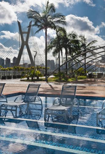 a pool with chairs and a bridge in the background at Novotel Sao Paulo Morumbi in Sao Paulo