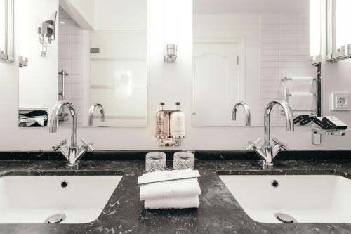 a bathroom with two sinks and two mirrors at Hotel Borg by Keahotels in Reykjavík