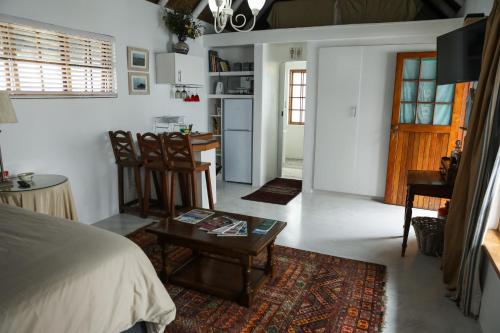 1 dormitorio con cama, mesa y cocina en Milkwood Way, en St Francis Bay