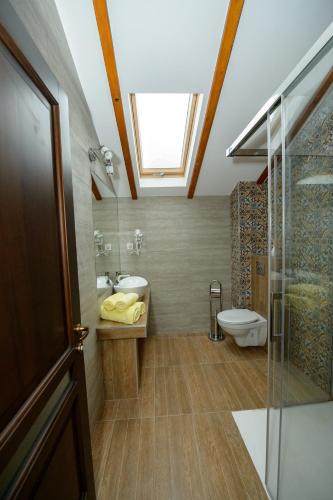 a bathroom with a sink and a toilet and a skylight at Casa Bucatarului in Bălnaca