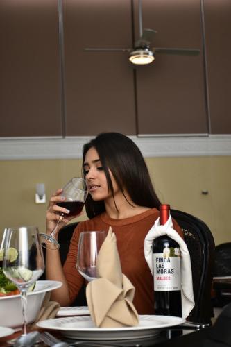 a woman sitting at a table drinking a glass of wine at Hotel Residencial in Mérida