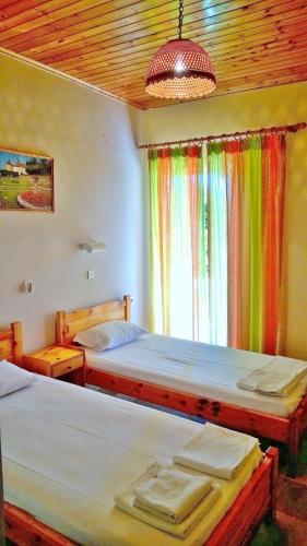 two beds in a room with a window with rainbow curtains at NEFELI House in Lefkimmi