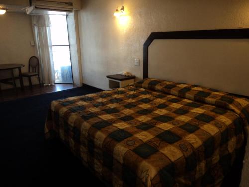 a hotel room with a bed with a checkered blanket at Hotel San Luis de Nogales in Heroica Nogales