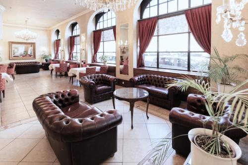 a lobby with leather couches and tables and windows at Hotel Monopol - Central Station in Frankfurt/Main