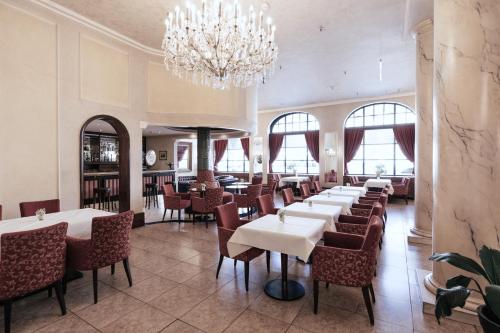 a dining room with tables and chairs and a chandelier at Hotel Monopol - Central Station in Frankfurt/Main