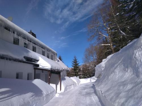 a house covered in snow next to a building at Greizer Kammhütte Gaststätte & Pension in Klingenthal