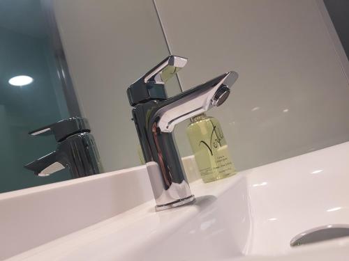 a bathroom sink with a faucet in front of a mirror at easyHotel London City Shoreditch in London