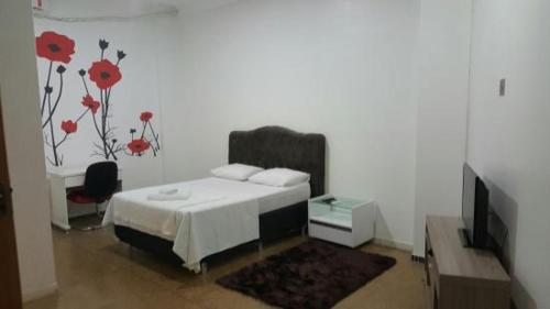 een slaapkamer met een bed met een bloem op de muur bij Hotel Roma in Edéia