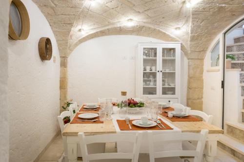 a dining room with a table and white chairs at Amatè Suite in Lecce