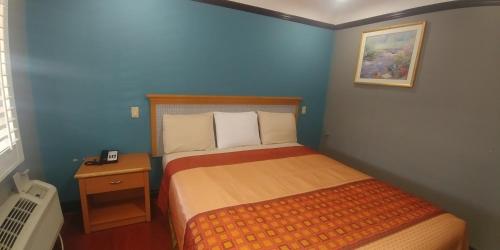 Dormitorio pequeño con cama en habitación azul en Travel Eagle Inn Motel en Long Beach