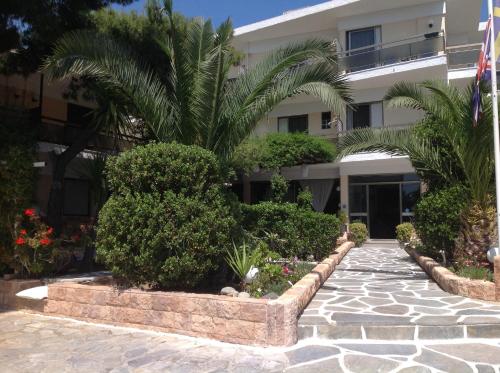 a building with a palm tree in front of it at Angela Hotel in Agia Marina Aegina