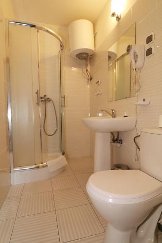 a bathroom with a shower and a toilet and a sink at Hotel Adria in Rumia