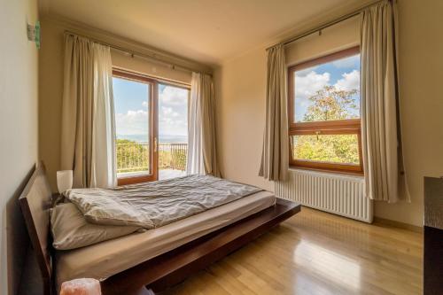 a bedroom with a bed and two large windows at Luxury Green Villa in Budapest