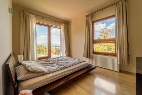 ブダペストにあるLuxury Green Villaのベッドルーム1室(ベッド1台、大きな窓2つ付)