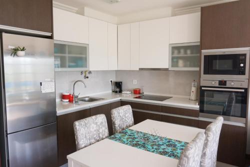 a kitchen with white cabinets and a table and chairs at Magoito Sea View Apartment in Lisbon