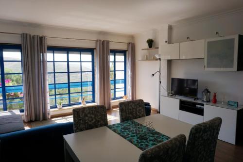 a living room with a table and chairs and a kitchen at Magoito Sea View Apartment in Lisbon