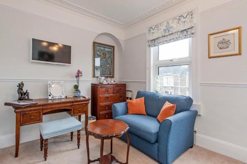 a living room with a blue chair and a desk at Apple Tree boutique B&B in Bath