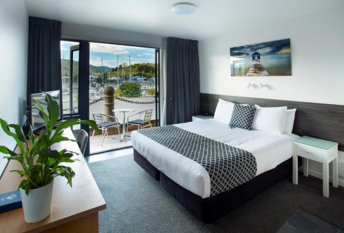 um quarto de hotel com uma cama e uma varanda em Harbourside Lodge em Nelson