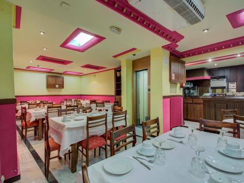 a restaurant with white tables and chairs and pink walls at Emperatriz II in Salamanca
