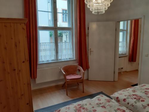 a bedroom with a bed and a chair and windows at Ferienwohnung Am Nauener Tor in Potsdam