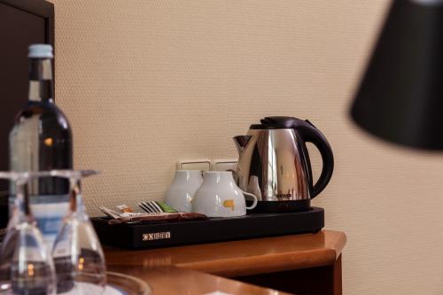 einen Wasserkocher und Tassen auf dem Tisch mit einer Flasche Wein in der Unterkunft SensCity Hotel Berlin Spandau in Berlin