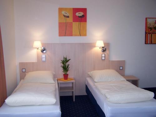 una habitación con 2 camas y una planta en la pared en Landgasthof Hock, en Großostheim