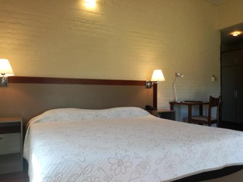 a bedroom with a large white bed with two lamps at Hotel Juana de Ibarbourou in Melo