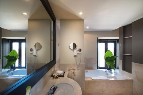 een badkamer met een bad, een wastafel en spiegels bij Hodelpa Nicolás de Ovando in Santo Domingo