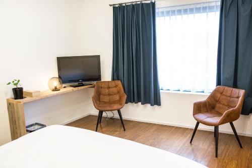 1 Schlafzimmer mit 2 Stühlen und einem Schreibtisch mit einem TV in der Unterkunft BNB Nest in Gent